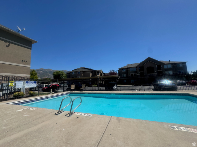 909 South Main Street, Unit F Layton, UT 84041 - Photo 20 of 20 Inviting swimming pool with an integrated ladder, surrounded by a concrete deck and secure perimeter fencing