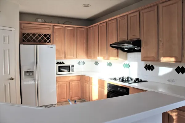 a kitchen with stainless steel appliances a refrigerator a stove and wooden cabinets