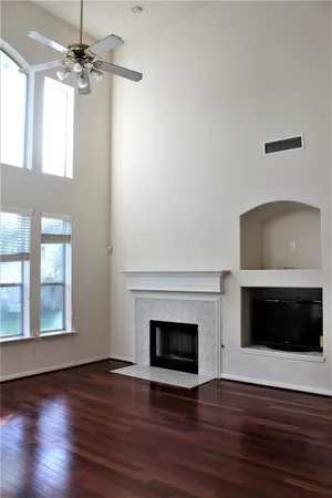 a view of an empty room with wooden floor fireplace and a window