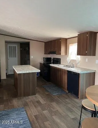 a kitchen with stainless steel appliances a sink a stove a refrigerator cabinets and a window