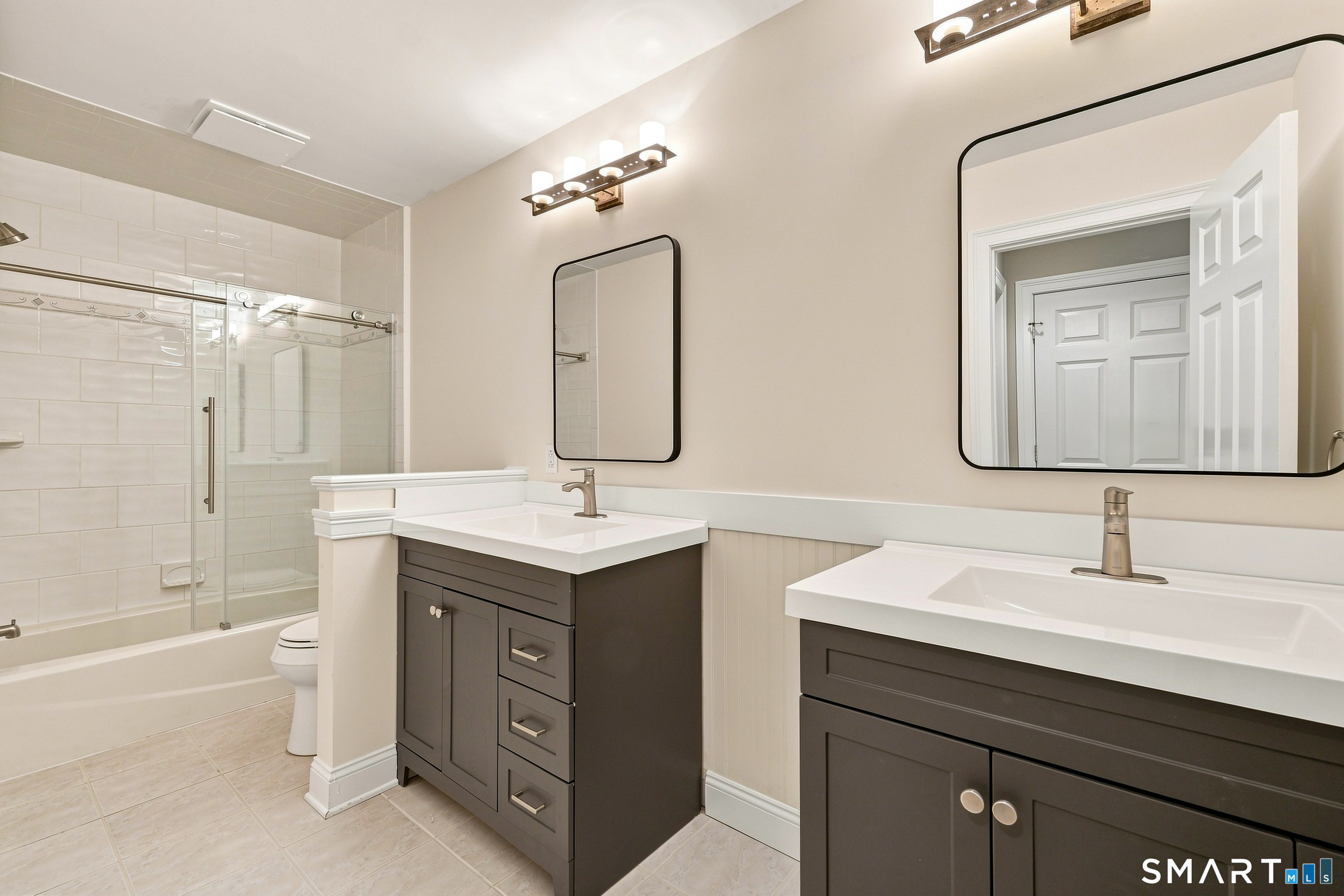 122 Lower Road Guilford, CT 06437 - Photo 25 of 39 Newly updated full bath on the second floor offers tile floor, two vanities, and combination tub/shower with tile surround & glass enclosure.