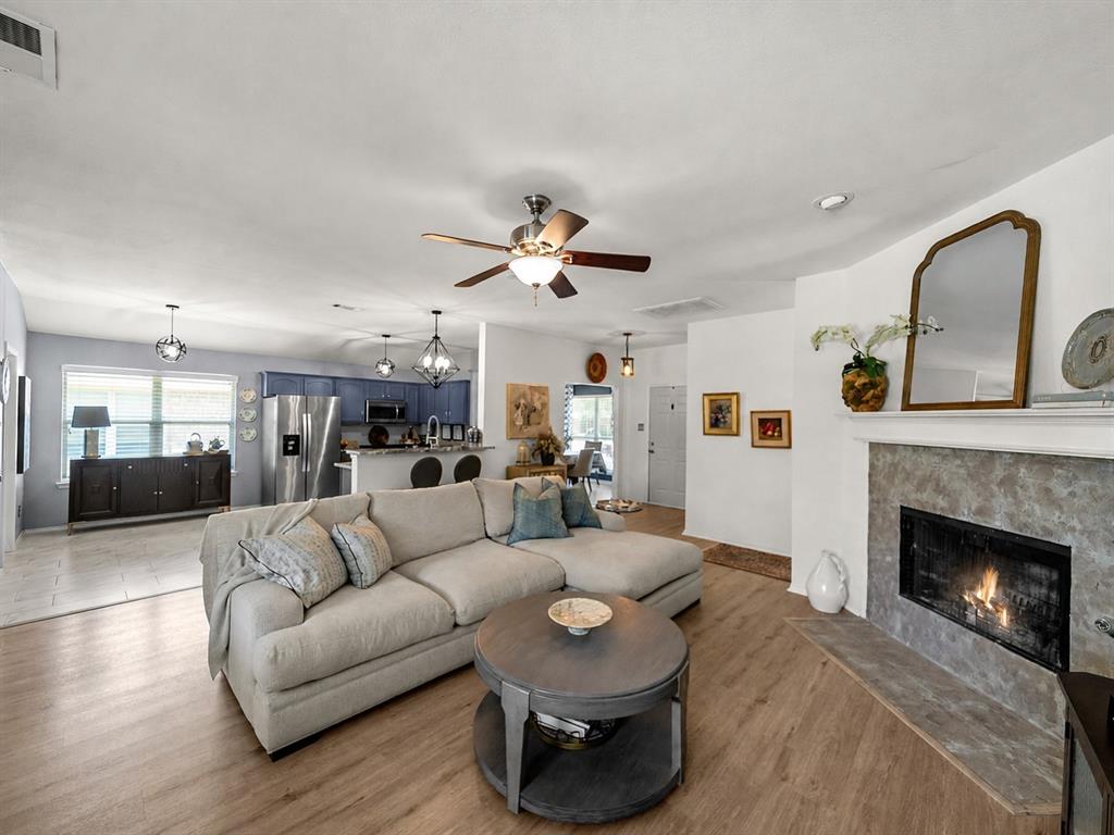 204 Arbor Ridge Drive Allen, TX 75002 - Photo 10 of 36 Open-concept living area featuring wood-finish flooring, a contemporary fireplace with a stone-look surround and hearth, and a ceiling fan