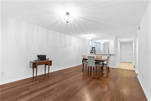 a dining room with furniture wooden floor a potted plant a painting and a chandelier