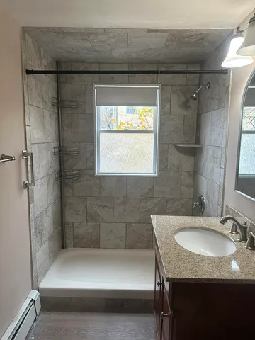 a bathroom with a granite countertop sink a mirror and shower