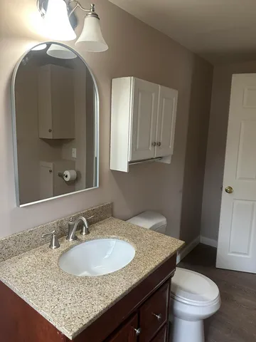 a bathroom with a granite countertop sink a toilet and mirror