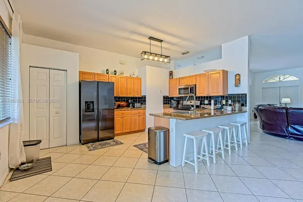 a kitchen with stainless steel appliances kitchen island granite countertop a refrigerator and a sink