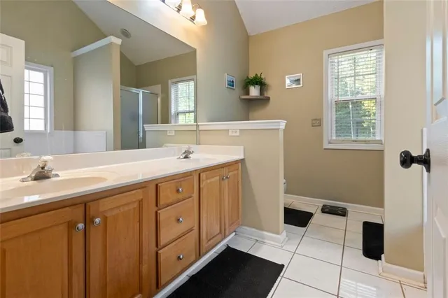 a spacious bathroom with a double vanity sink a mirror and a shower