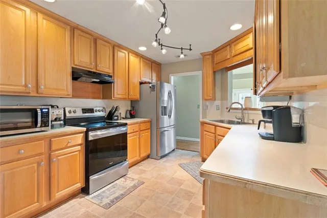 a kitchen with stainless steel appliances granite countertop a sink a stove and a refrigerator