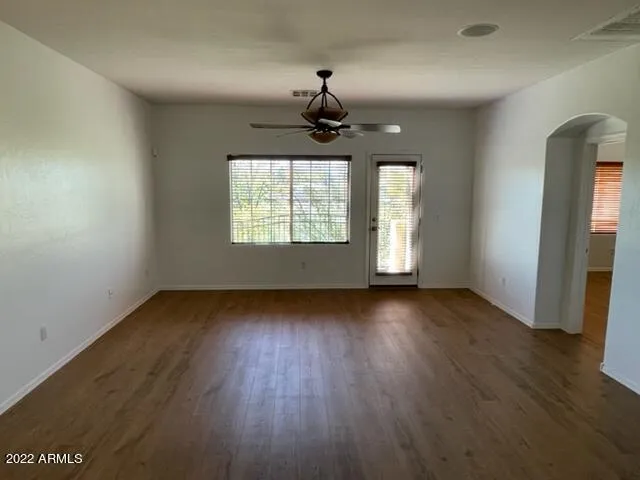 an empty room with wooden floor chandelier and windows