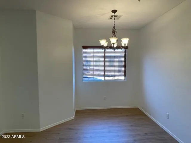 an empty room with wooden floor chandelier and window