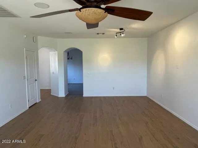 an empty room with a ceiling fan and wooden floor