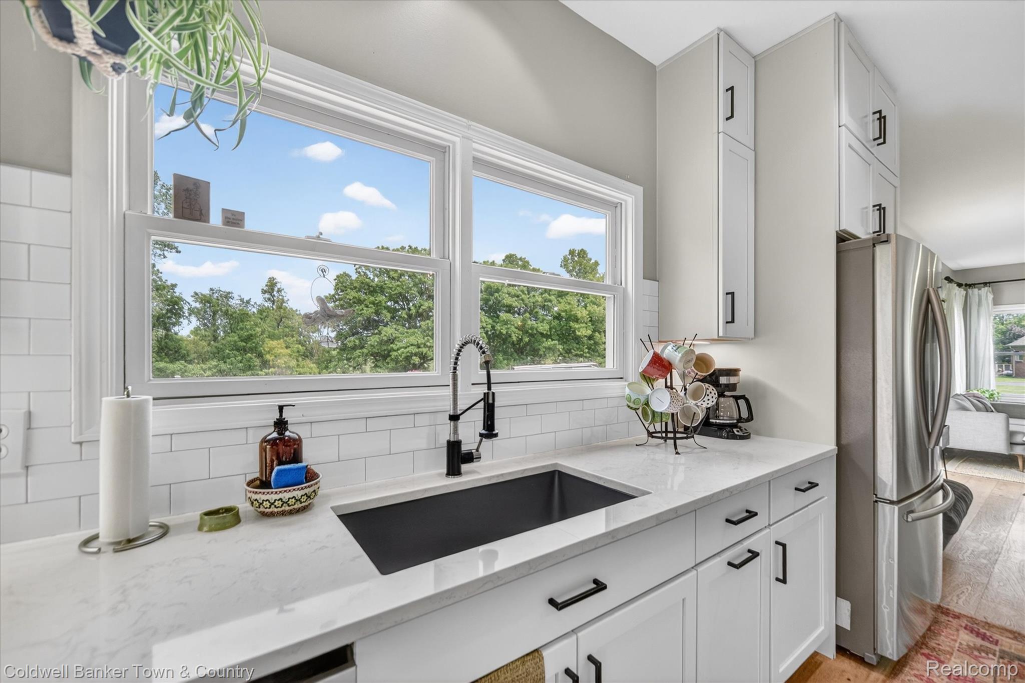 918 Gray Fox Court Howell, MI 48843 - Photo 13 of 84 Kitchen featuring a white subway tile backsplash, white shaker-style cabinetry with matte black hardware, stone-finish countertops, and a black undermount sink with a gooseneck faucet