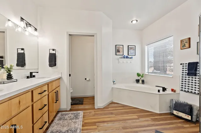 a spacious bathroom with double vanity a bathtub and a window