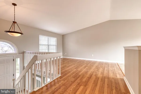 a view of an empty room with wooden floor and windows