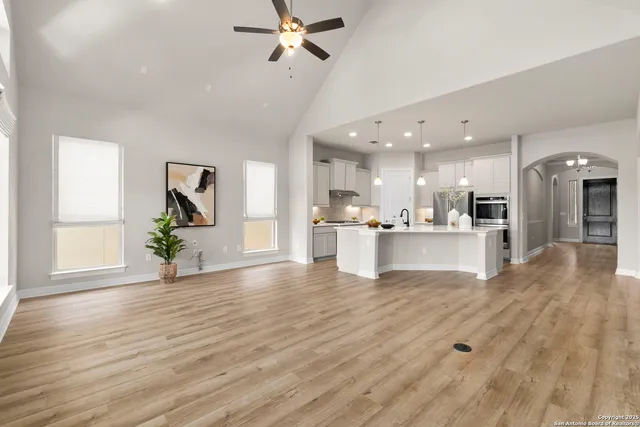 a view of an empty room and kitchen with sink wooden floor and a window