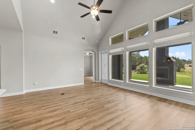 a view of an empty room with a window and wooden floor