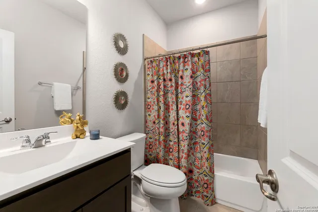 a bathroom with a sink a toilet and shower curtain