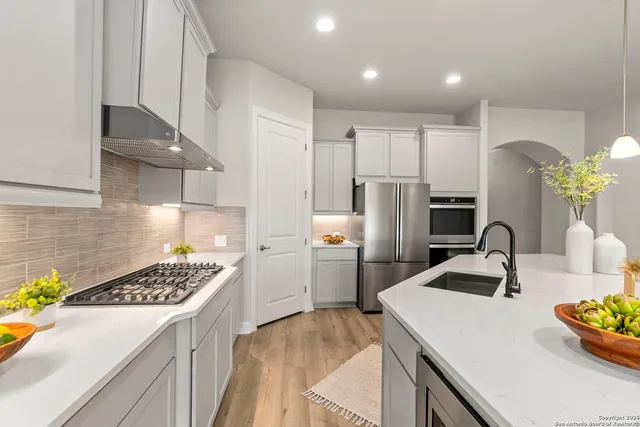 a kitchen that has a lot of cabinets a sink and wooden floor