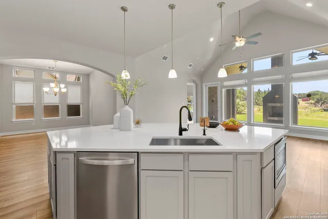 a kitchen with kitchen island granite countertop a sink a counter top space and living room view