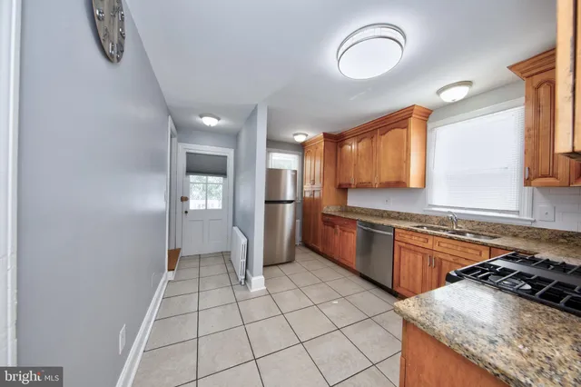 a kitchen with granite countertop a stove a sink and a refrigerator