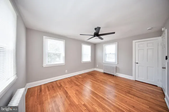a view of empty room with wooden floor and fan