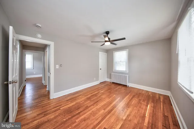 a view of empty room with wooden floor and fan
