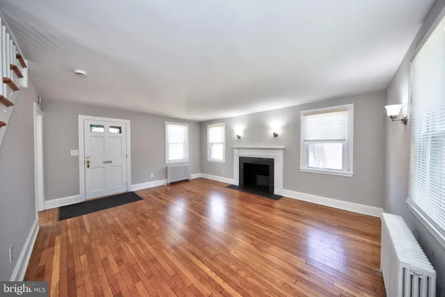 an empty room with wooden floor fireplace and windows
