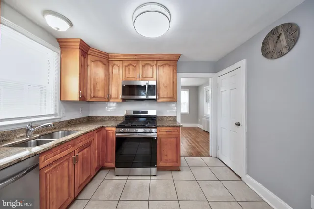 a large kitchen with stainless steel appliances granite countertop a stove a sink and a microwave