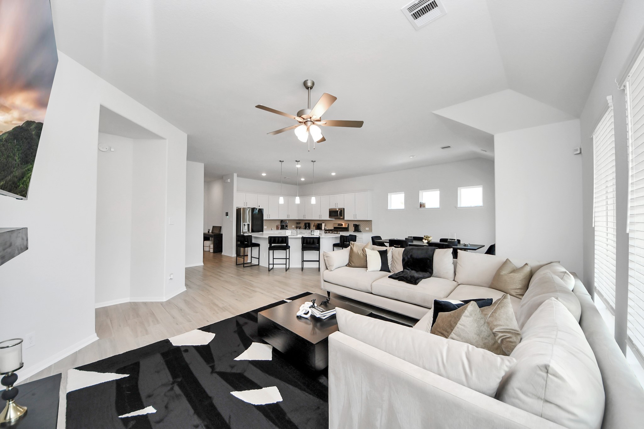 10603 Juniper Br Drive Rosharon, TX 77583 - Photo 25 of 50 Spacious open-concept living area with modern design, featuring a large sectional sofa, ceiling fan, and abundant natural light. The sleek kitchen includes a generous island with bar seating, stainless steel appliances, and contemporary cabinetry. Ideal for entertaining and family gatherings.