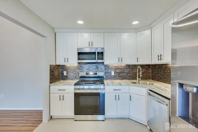 a kitchen with white cabinets stainless steel appliances and sink
