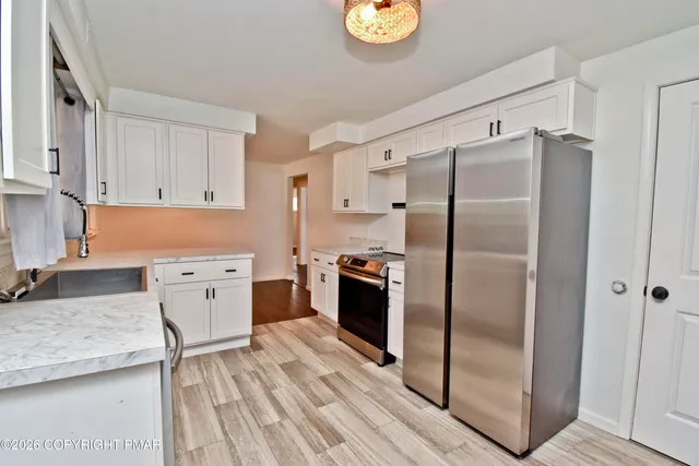 a kitchen with stainless steel appliances granite countertop a refrigerator a stove and a sink with granite countertops