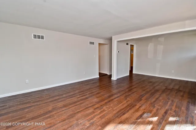 a view of an empty room with wooden floor and closet