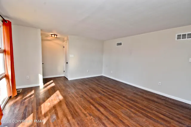 a view of a room with wooden floor and a window