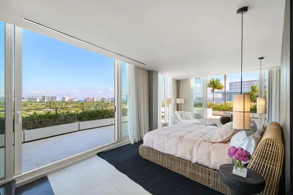 a bedroom with a bed and large windows