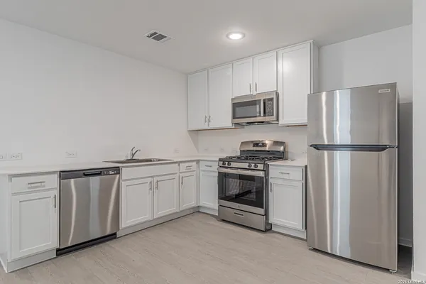 a kitchen with granite countertop white cabinets and stainless steel appliances