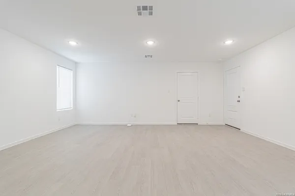 an empty room with white wall and windows