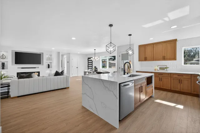 a large kitchen with stainless steel appliances a large counter top a sink a stove and a wooden floor