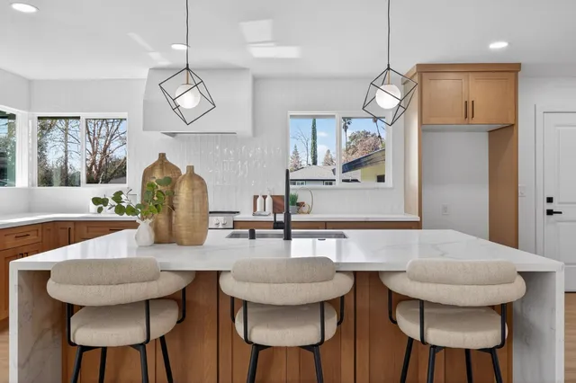 a kitchen with stainless steel appliances granite countertop a dining table chairs and a chandelier