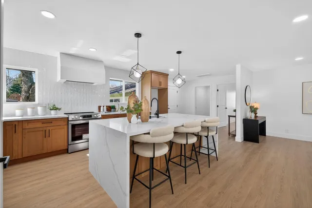 a kitchen with stainless steel appliances kitchen island granite countertop a table chairs sink and cabinets