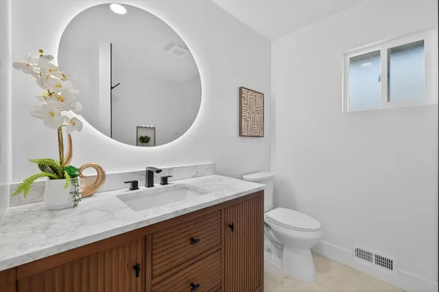 a bathroom with a granite countertop sink a toilet and mirror