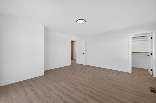 a view of an empty room with wooden floor and a window