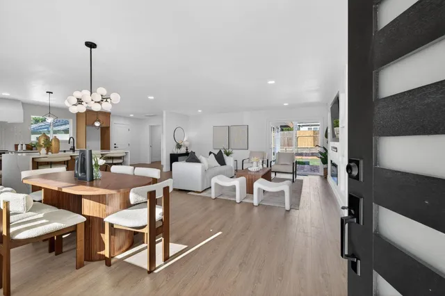 a view of a dining room and livingroom with furniture wooden floor a chandelier