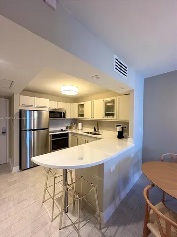 a kitchen with stainless steel appliances kitchen island granite countertop a table chairs and a refrigerator