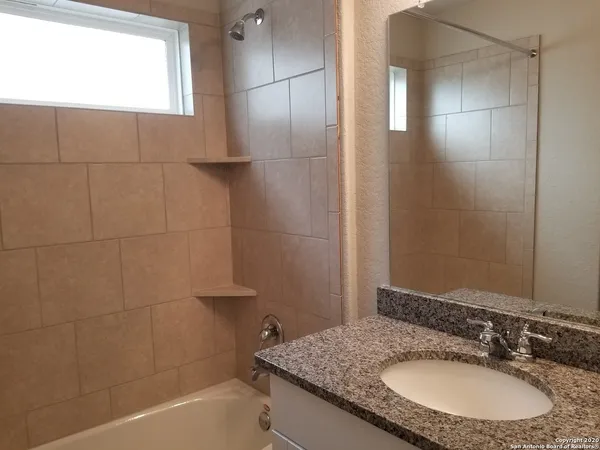 a bathroom with a granite countertop sink a mirror and a bathtub