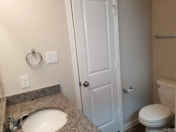 a bathroom with a granite countertop toilet sink and mirror