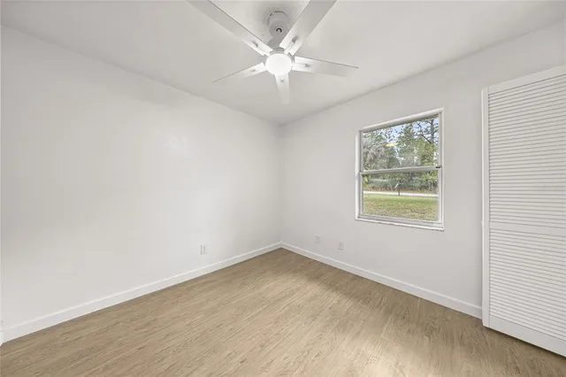 an empty room with a chandelier fan and windows
