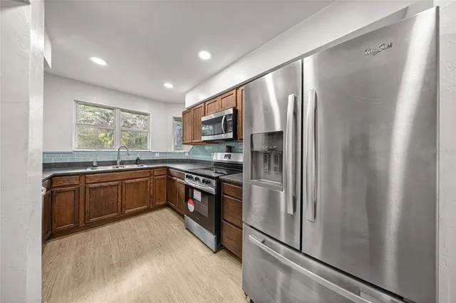 a kitchen with stainless steel appliances granite countertop a refrigerator and a stove top oven