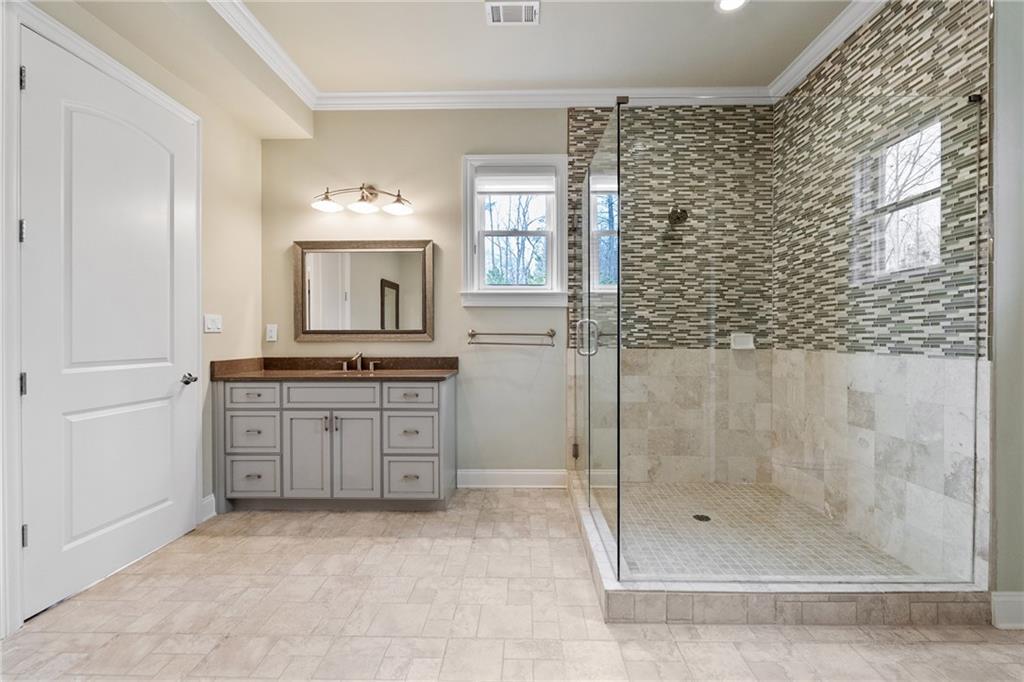 14560 Wood Road Milton, GA 30004 - Photo 58 of 74 a bathroom with a granite countertop sink a mirror a shower and a bathtub