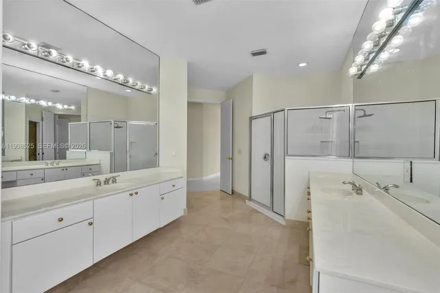 a spacious bathroom with a double vanity sink mirror and shower