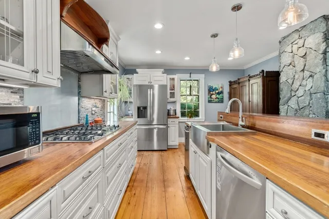 a kitchen with stainless steel appliances granite countertop a refrigerator a sink dishwasher a stove and white countertops with wooden floor